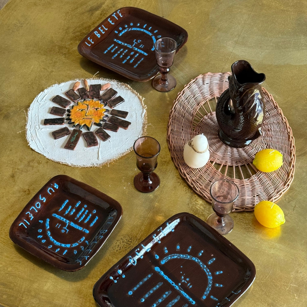 Vue de dessus d’une table stylisée avec assiettes décorées soleil, pichet en céramique et accessoires naturels ambiance estivale