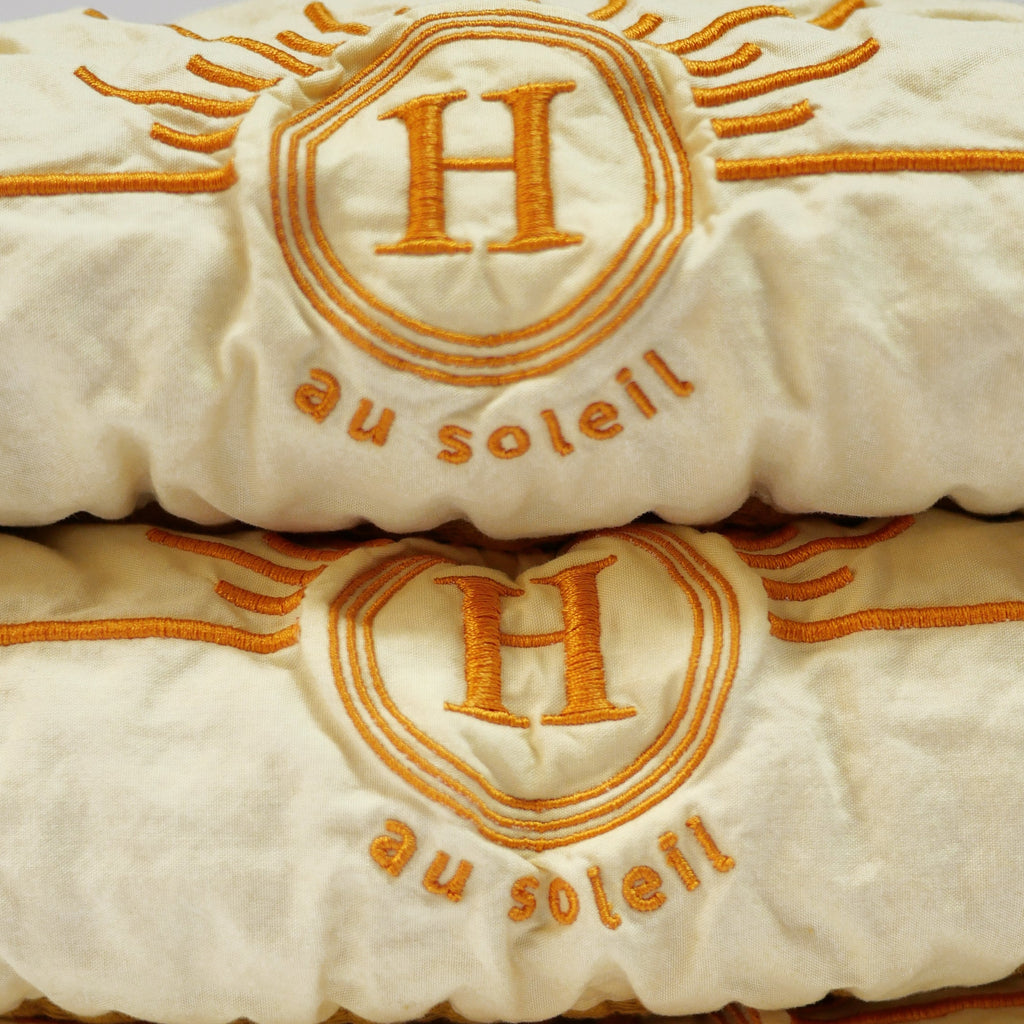 Détail serviettes gaufrées de bain  en coton nid d’abeille de différentes couleurs moutarde, ornées de broderies soleil signées Honoré.