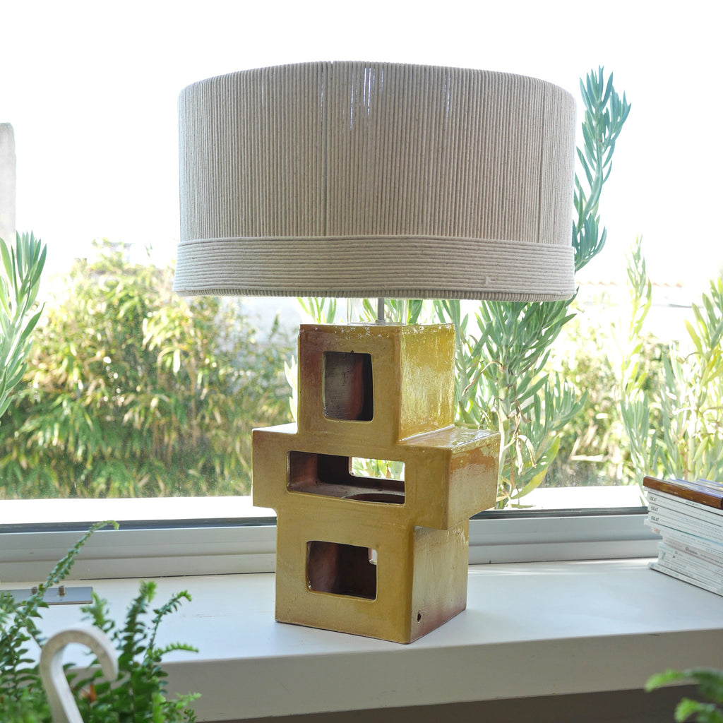 Lampe à poser en céramique artisanale jaune brulé, forme géométrique sculpturale avec abat-jour en corde — luminaire design pour salon ou chambre.