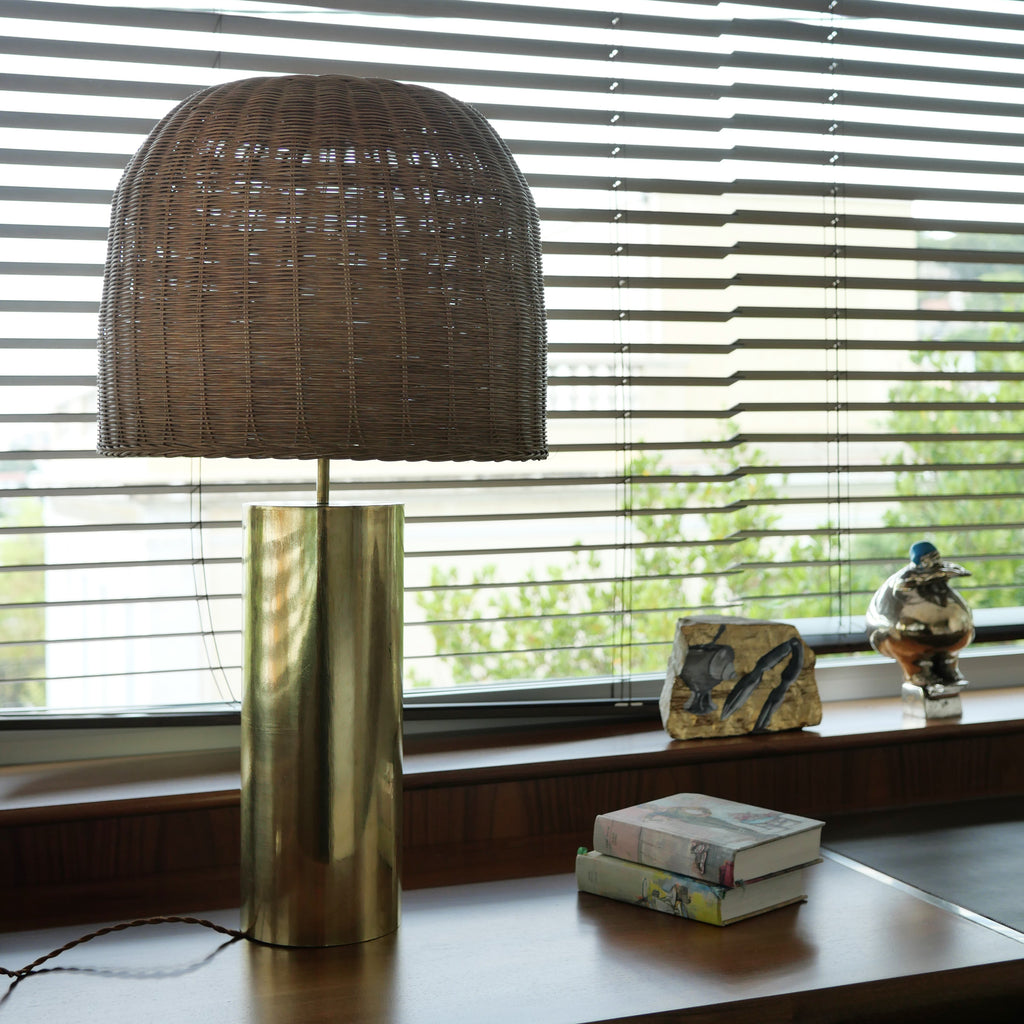 lampe sur pied a poser fungo doré laiton abat rotin foncé sur bureau store en arriere plan 